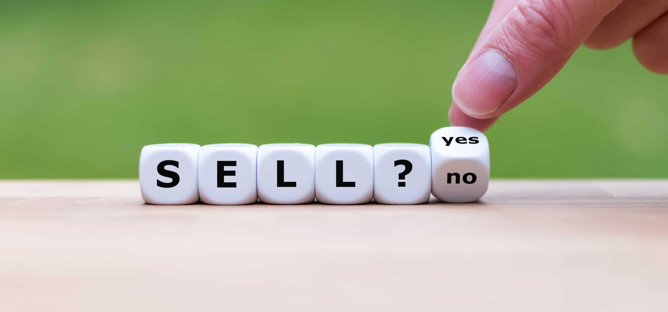 Time to sell? Hand turns a dice and changes the word “no” to “ye Sell yes no scaled